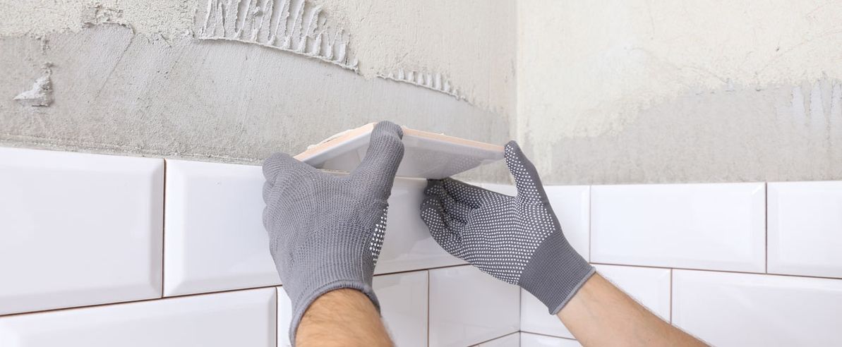 Fliesenleger - aufgenommen im Moment, bei dem er eine Fliese an einem Rohbau anbringen will